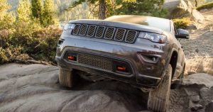 A 2018 Jeep Grand Cherokee climbing over a rocky hill.