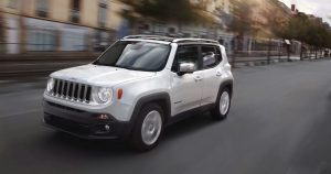 A white 2019 Jeep Renegade driving down a city street.