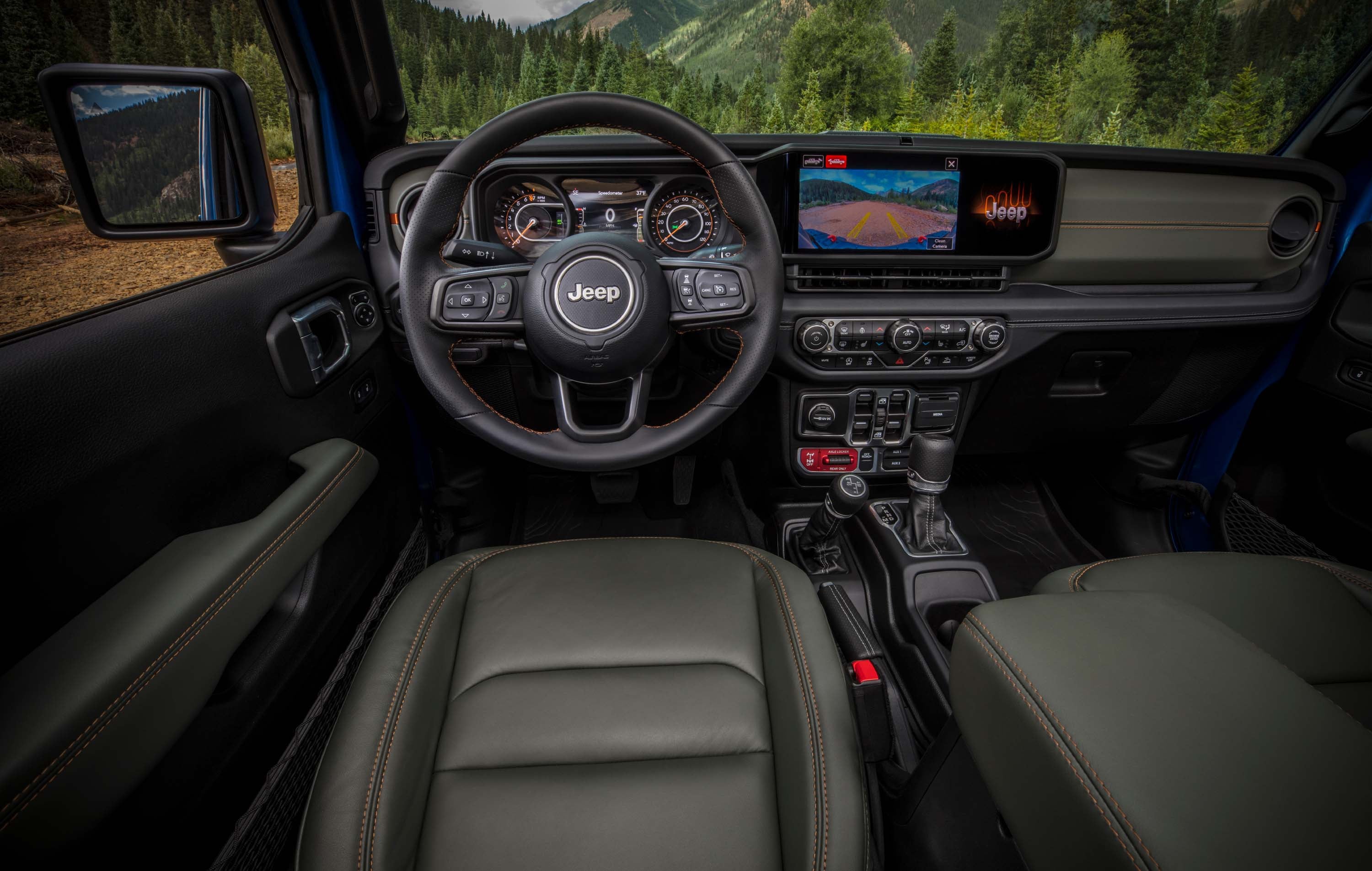 Interior view of a Jeep vehicle, showing the steering wheel, dashboard with infotainment screen, and front seats.